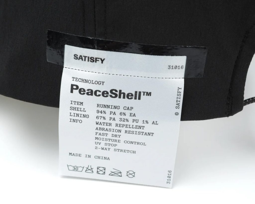 Étiquette extérieure à découper de la casquette Satisfy PeaceShell indiquant la technologie, la composition et les propriétés techniques