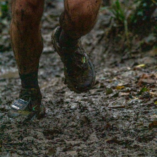 Chaussures de trail couvertes de boue sur un chemin de la forêt de Rennes au Trail du Porteur d'Eau