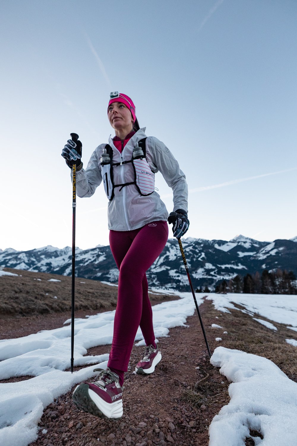 La Prodigio Max GTX en configuration ultra-trail, gilet et bâtons La Prodigio Max GTX en usage ultra, coureuse équipée d'un gilet d'hydratation et de bâtons sur un sentier enneigé