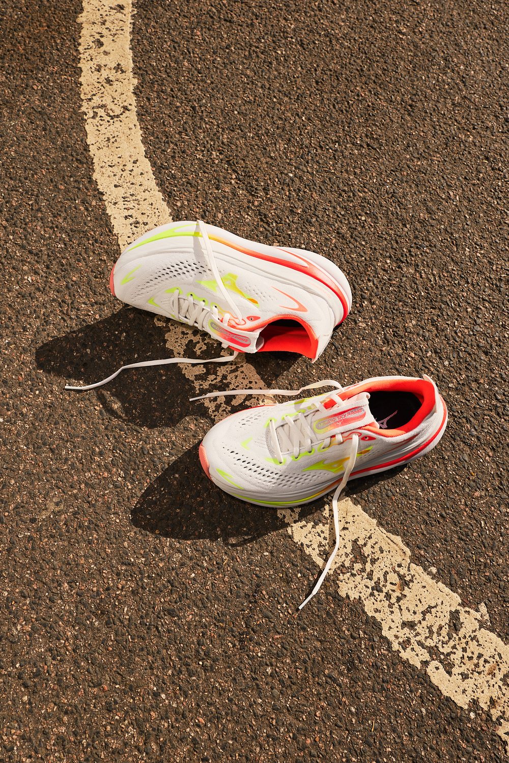 La Mizuno Sky Prime en coloris blanc, corail et jaune fluo, posée sur le bitume